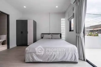 Modern bedroom with minimalist design and large window for natural light.