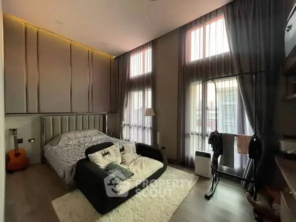 Luxurious bedroom with high ceilings, modern decor, and large windows for natural light.