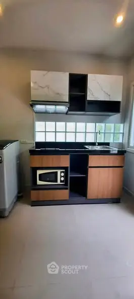 Modern kitchen with sleek cabinetry and built-in microwave, featuring a large window for natural light.