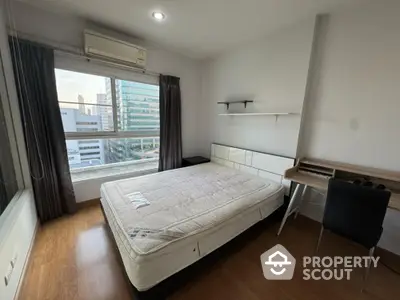 Modern bedroom with city view, featuring a comfortable bed and sleek desk setup.