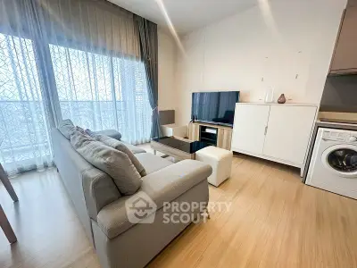 Modern living room with cozy gray sofa, TV, and washing machine in stylish apartment.