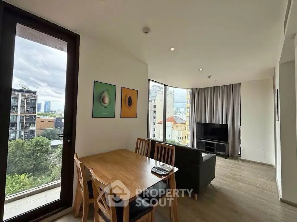 Spacious living room with large windows and modern decor, offering a stunning city view.