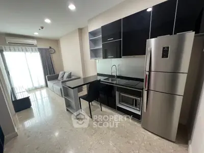 Modern open-layout kitchen with sleek appliances and cozy living area in a stylish apartment.