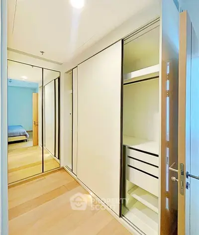 Spacious bedroom with mirrored sliding closet doors and ample storage space.