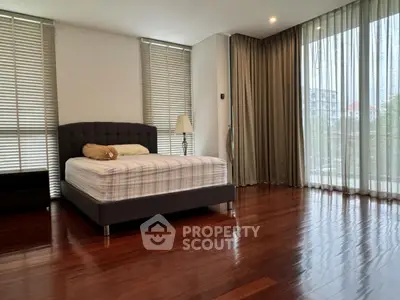 Spacious bedroom with large windows and elegant wooden flooring