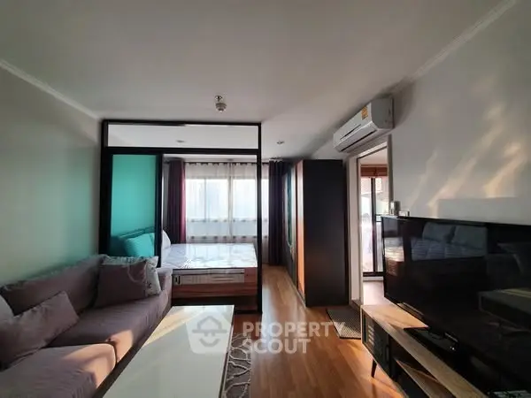 Modern apartment interior with cozy living room and bedroom, featuring wooden flooring and natural light.