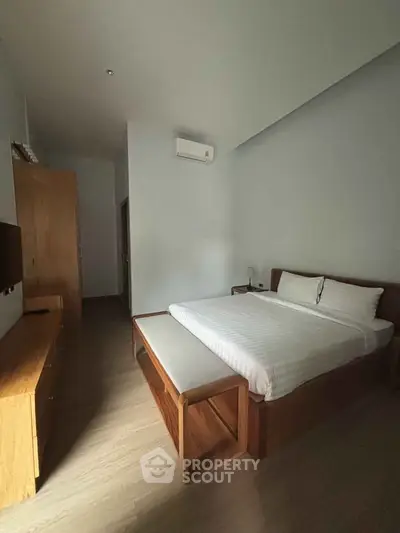 Spacious bedroom with modern wooden furniture and air conditioning in a cozy apartment.