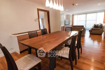 Spacious dining area with wooden table and modern lighting in open-plan living space.
