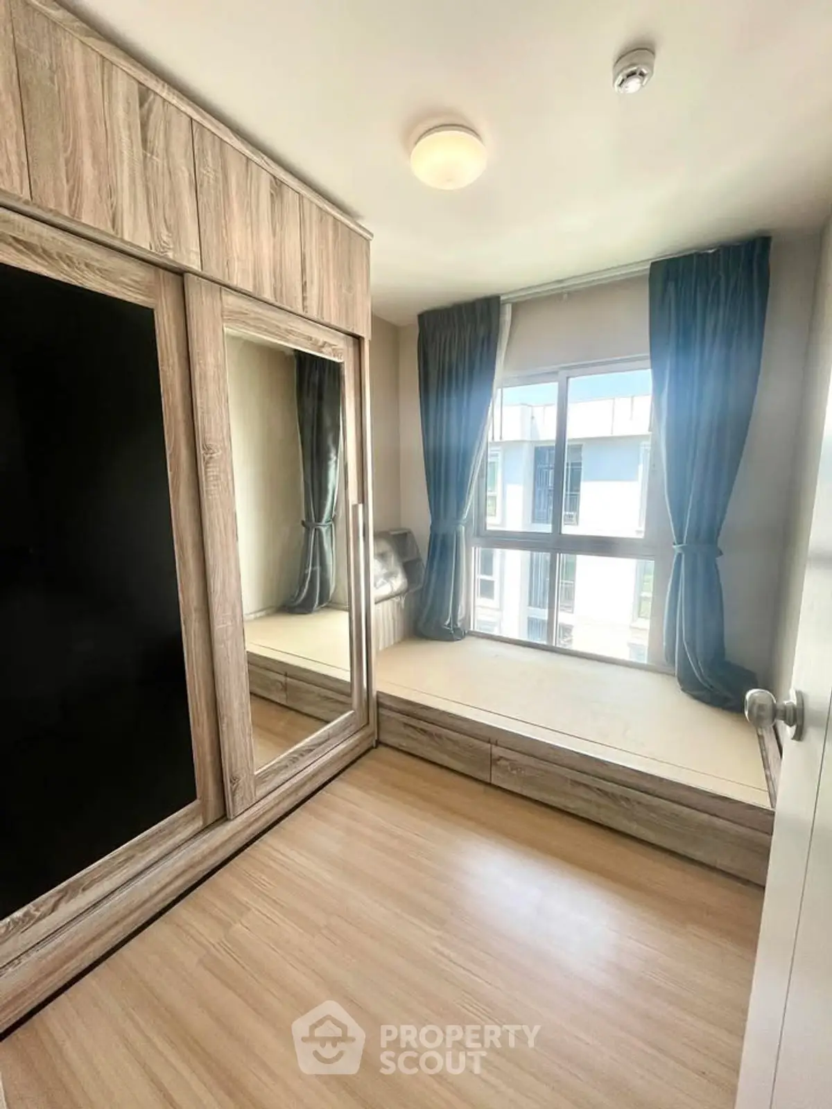 Cozy bedroom with large mirrored wardrobe and window view