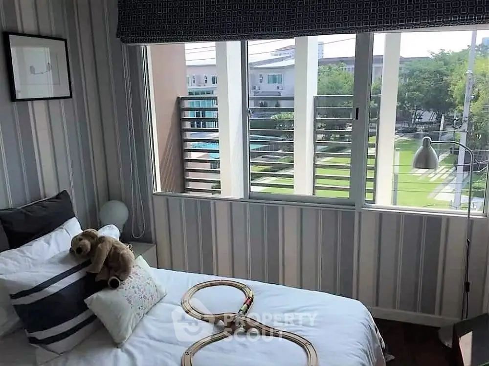 Cozy bedroom with a view of lush garden and pool, featuring stylish decor and ample natural light.