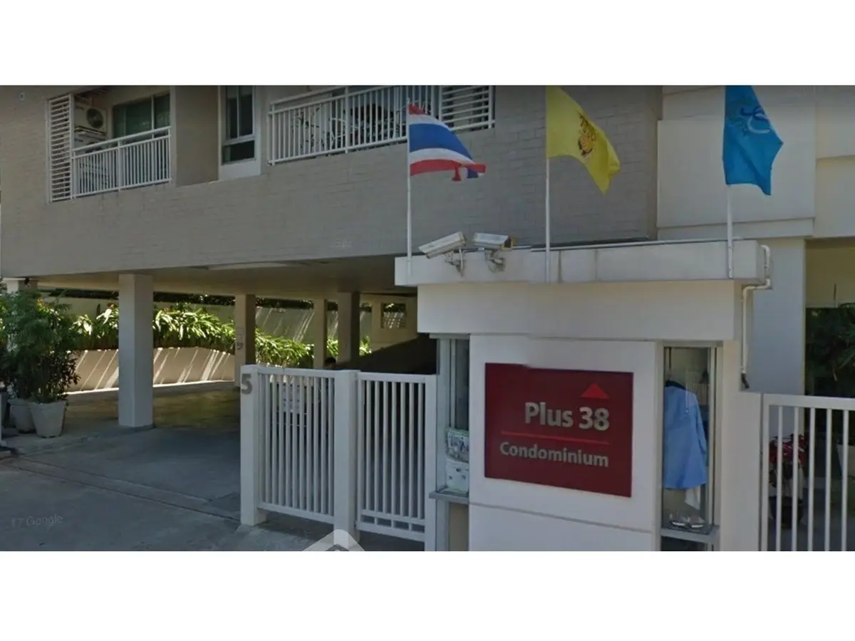 Modern condominium entrance with flags and secure gated access in urban setting.