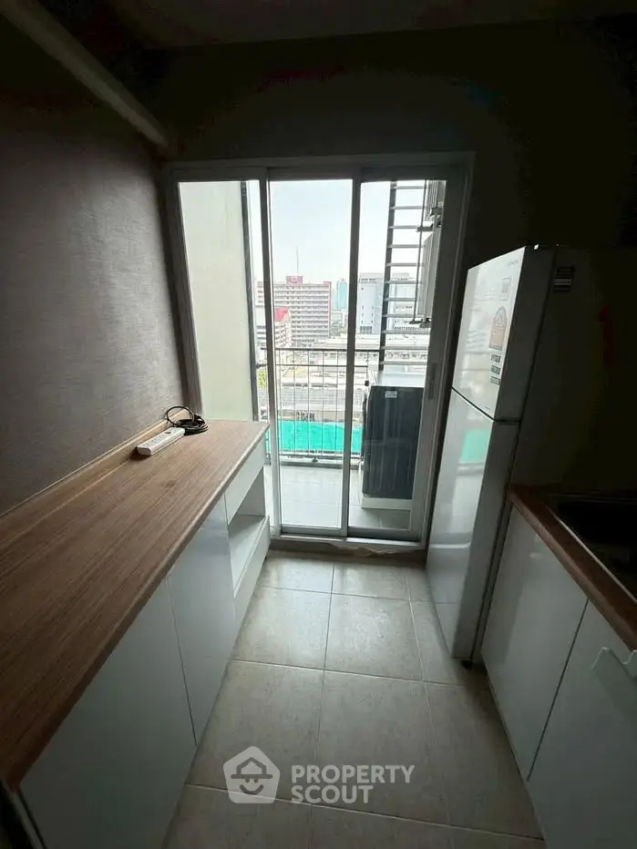 Compact kitchen with balcony view, featuring modern appliances and sleek countertops.