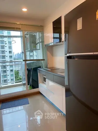 Modern kitchen with sleek appliances and balcony view in high-rise apartment.