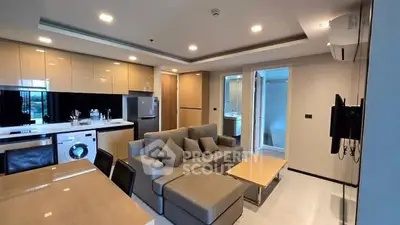 Modern open-layout living room with kitchen, featuring a washing machine and sleek furniture.