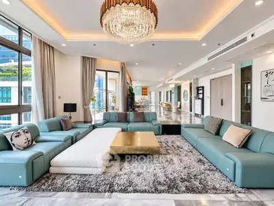Luxurious living room with modern decor, spacious seating, and elegant chandelier in high-end apartment.