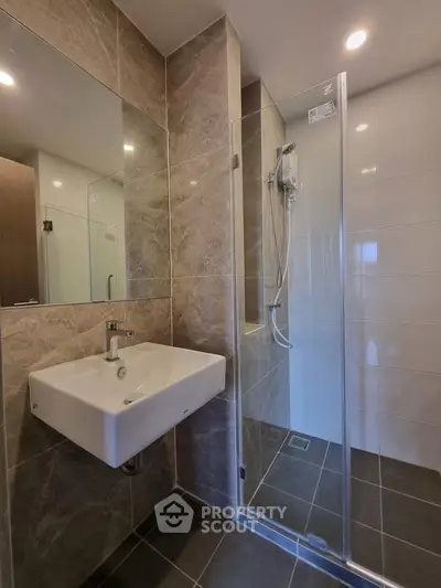 Modern bathroom with sleek design featuring a glass shower and stylish sink.