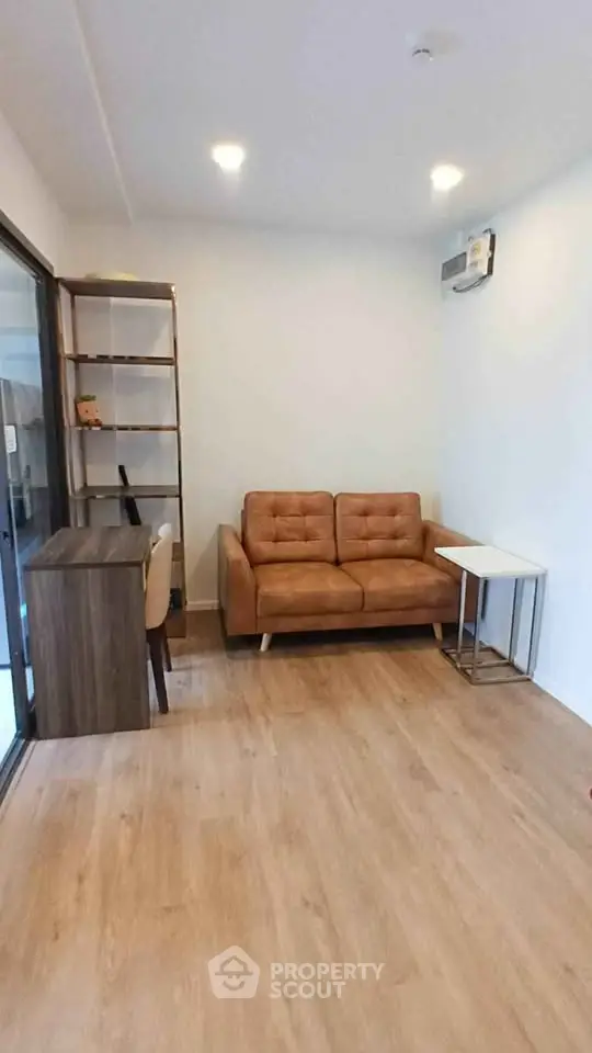 Cozy living room with brown leather sofa and wooden flooring, perfect for relaxation.