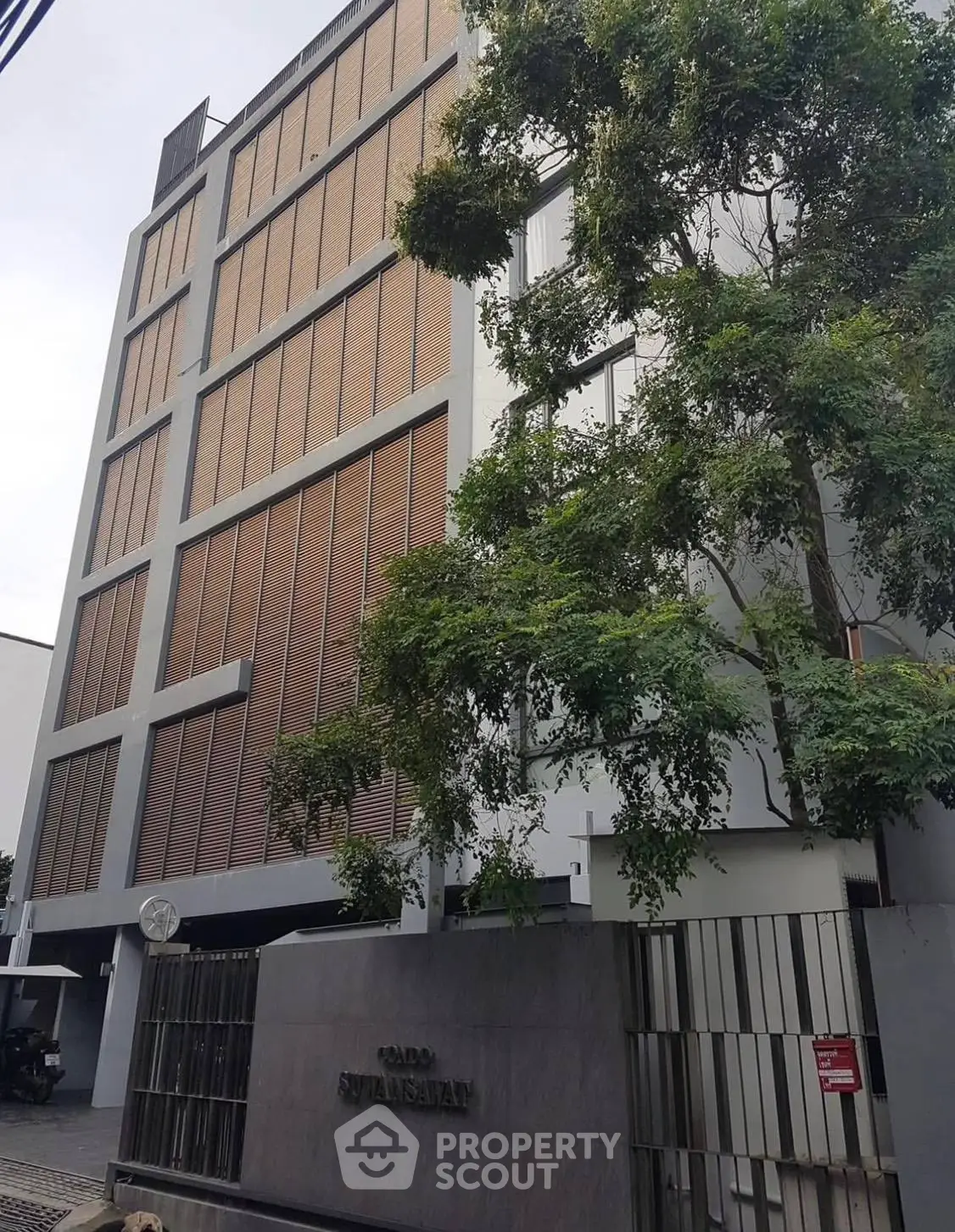 Modern apartment building with sleek facade and lush greenery in urban setting.