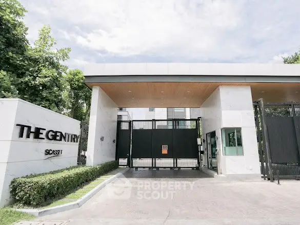 Luxurious gated entrance of The Gentry showcasing modern architecture and lush greenery.