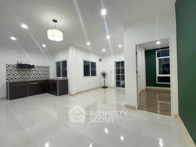 Spacious open-plan living area with modern kitchen and elegant lighting.