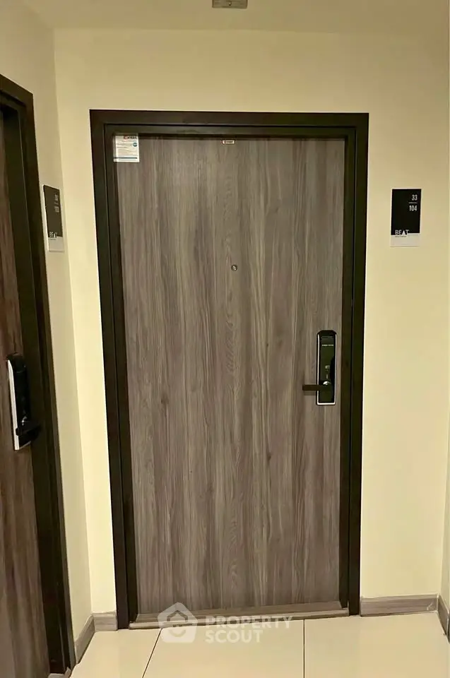 Modern apartment entrance with sleek wooden door and digital lock system.