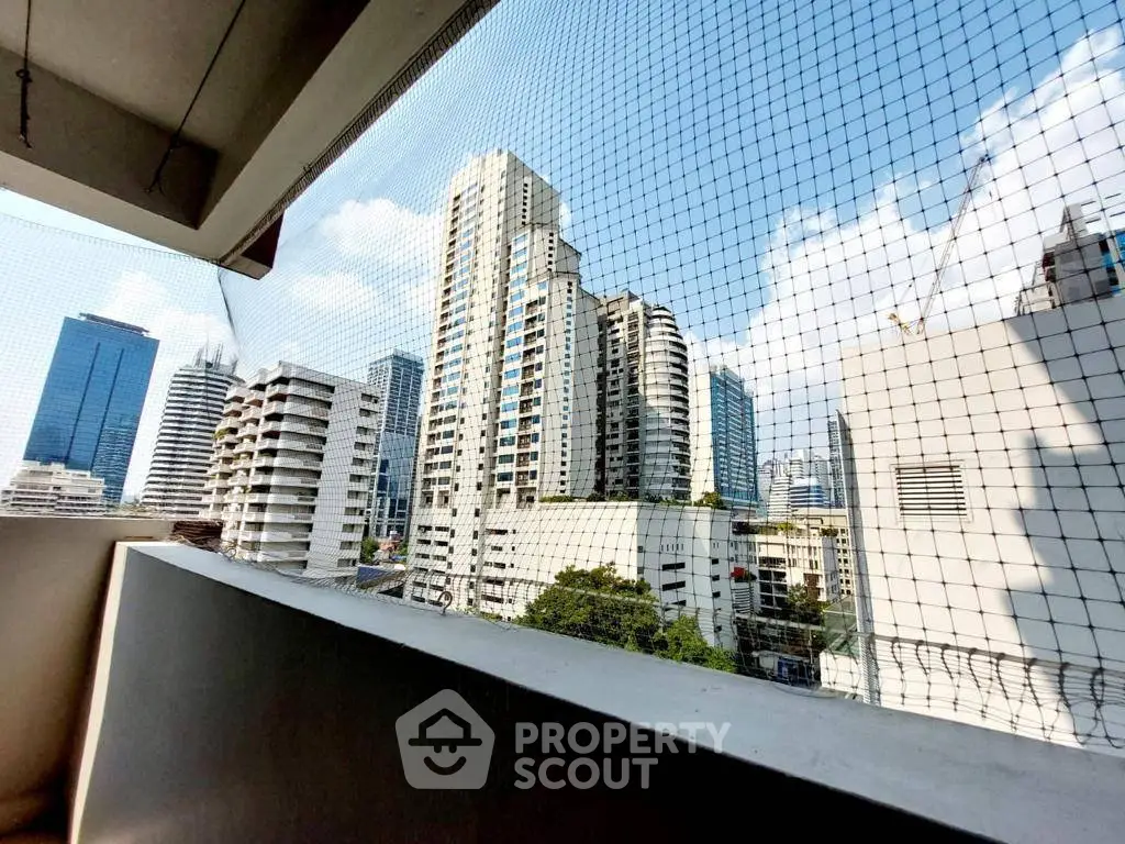 Stunning cityscape view from a high-rise balcony with safety netting, showcasing modern urban living.