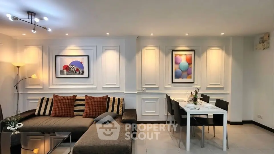 Elegant living room with modern decor and dining area, featuring stylish lighting and artwork.