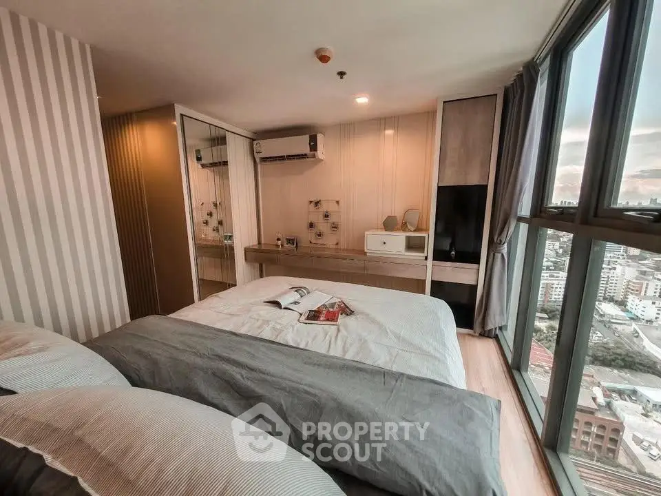 Modern bedroom with city view, featuring stylish decor and large windows for natural light.