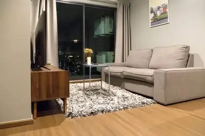 Modern living room with cozy sofa and city view through large window.