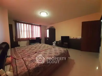 Spacious bedroom with large bed and ample natural light from window.