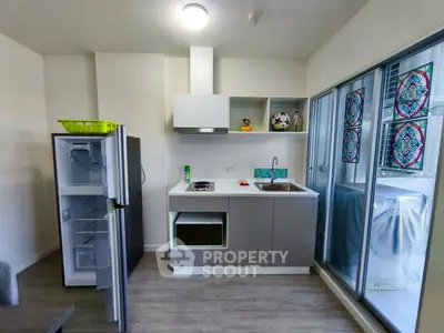 Modern kitchen with open fridge and sleek cabinetry in a compact apartment