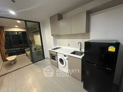 Modern apartment kitchen with sleek appliances and open layout leading to cozy living area.