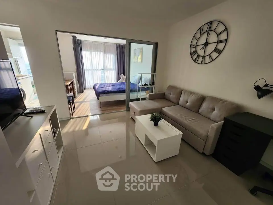 Modern living room with stylish decor and adjacent bedroom in open layout apartment.