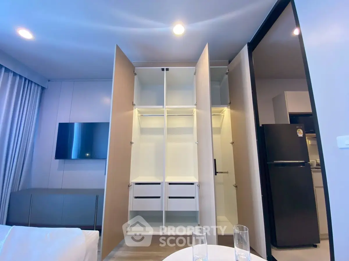 Modern apartment interior with open wardrobe and sleek kitchen appliances