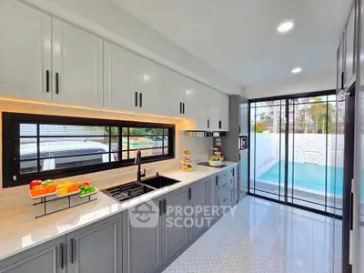 Modern kitchen with sleek cabinetry and pool view, featuring open layout and gas stove.