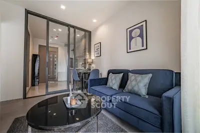 Modern living room with stylish blue sofa and glass partition in a contemporary apartment.