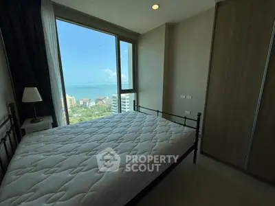 Cozy bedroom with stunning ocean view and large window in modern apartment.