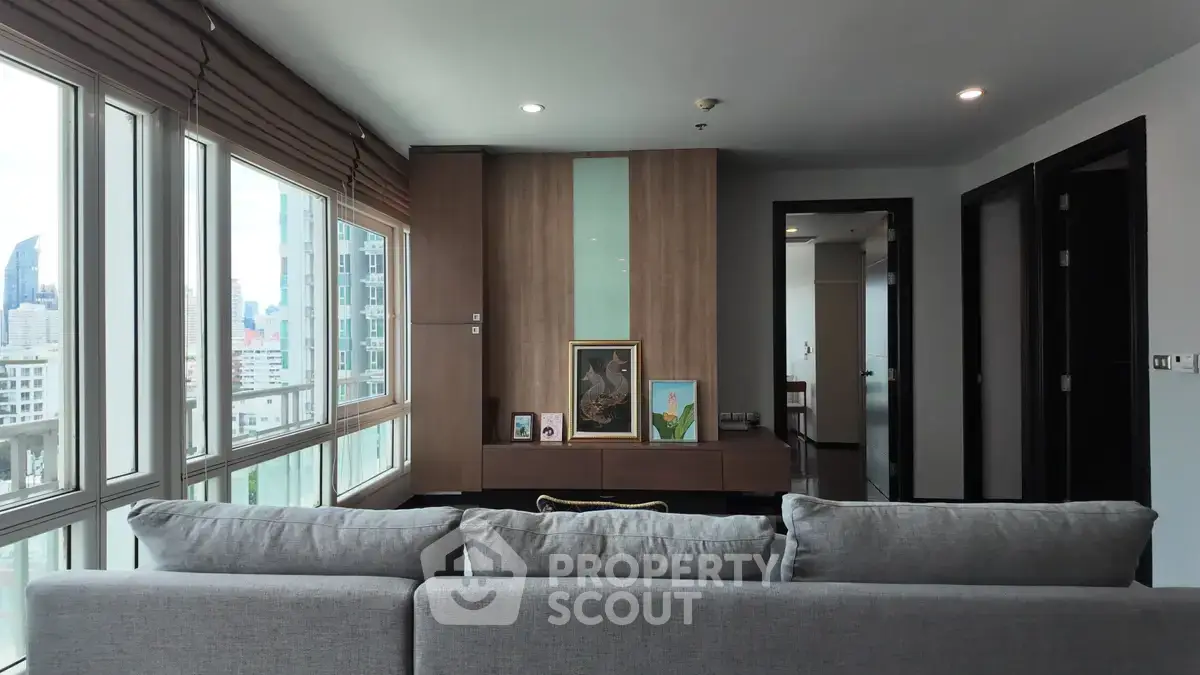 Modern living room with large windows and city view, featuring stylish decor and comfortable seating.