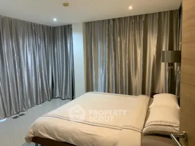 Spacious bedroom with elegant curtains and modern lighting in a luxury apartment.