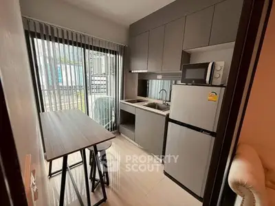 Modern compact kitchen with sleek cabinetry and dining area in urban apartment.