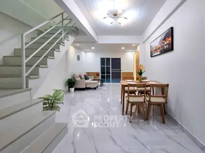 Spacious modern living room with elegant staircase and dining area, featuring sleek marble flooring and stylish decor.