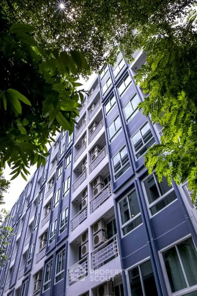 Modern apartment building exterior with lush greenery and blue facade