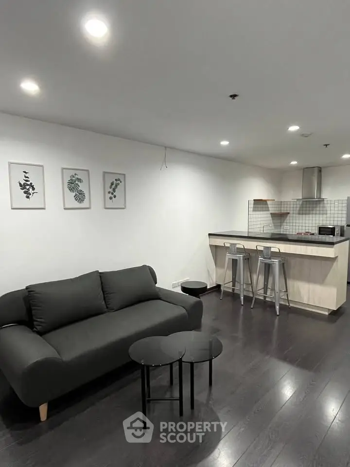 Modern living room with sleek black sofa and stylish open kitchen layout