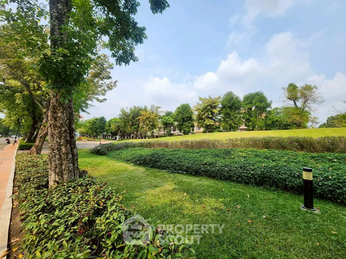 Lush green garden with trees and manicured hedges in a serene park setting.