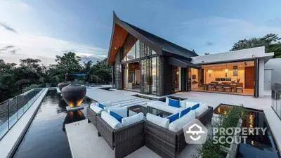 Luxurious modern villa with stunning pool and outdoor seating area at sunset.