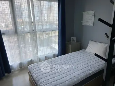Cozy bedroom with large window and modern decor in urban apartment.