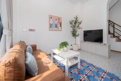 Stylish living room with modern decor, leather sofa, and flat-screen TV, perfect for relaxation and entertainment.