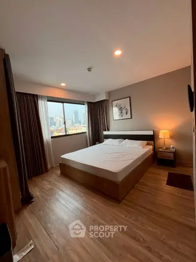 Spacious bedroom with city view, featuring modern decor and wooden flooring, ideal for urban living.