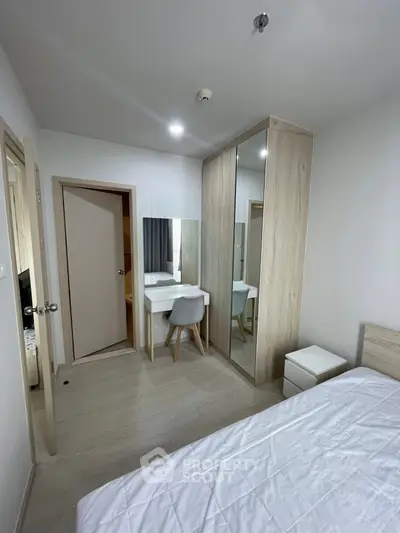 Modern bedroom with sleek furniture and mirrored wardrobe in a stylish apartment.
