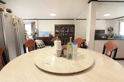 Spacious dining area with elegant round table and stylish chairs, perfect for family gatherings.